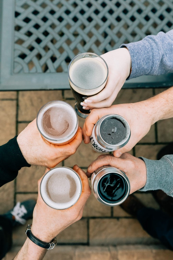 5 people holding beverages, cheering.